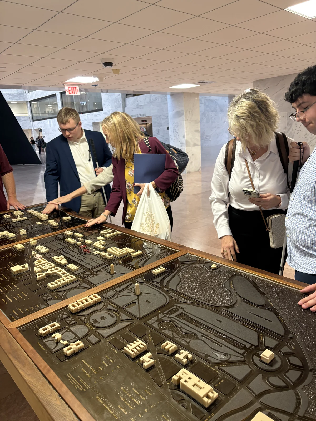 Visitors explore the details of a large tactile building model.