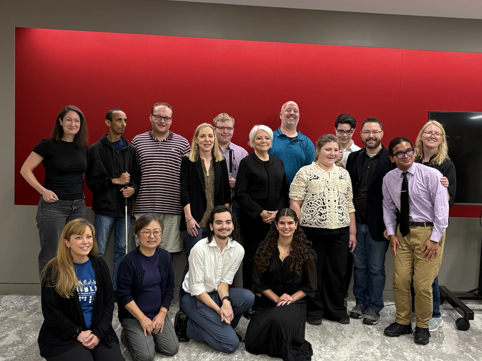 The group poses for a photo in a room with a red wall.