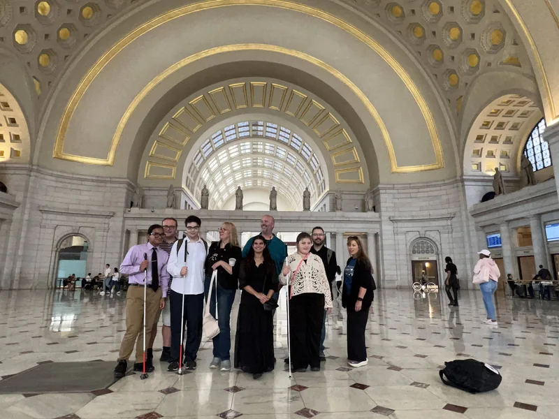 Members of the group stand beneath the tall arches of Union Station.