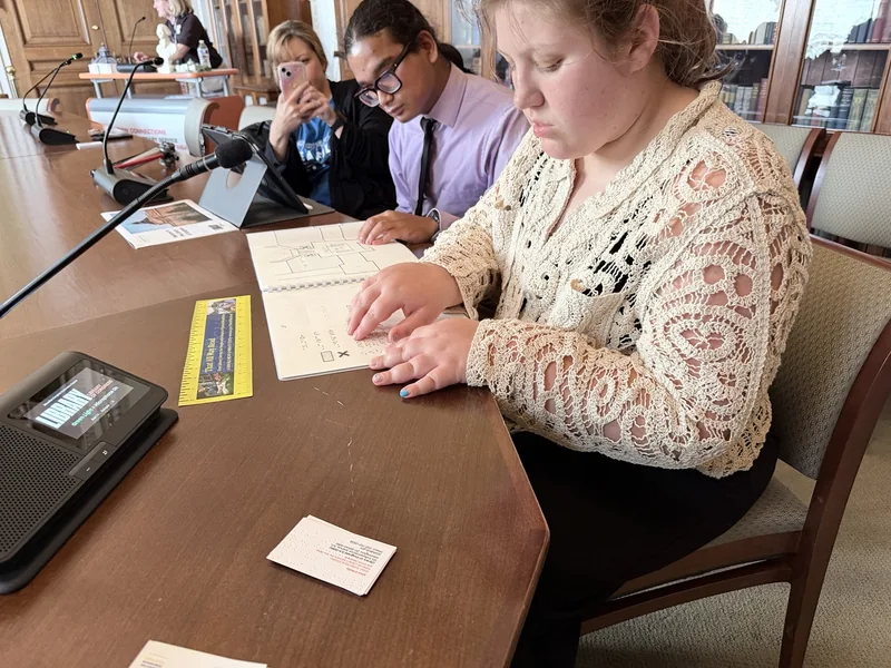 Isabelle explores a Braille and tactile guide at a Library of Congress table.