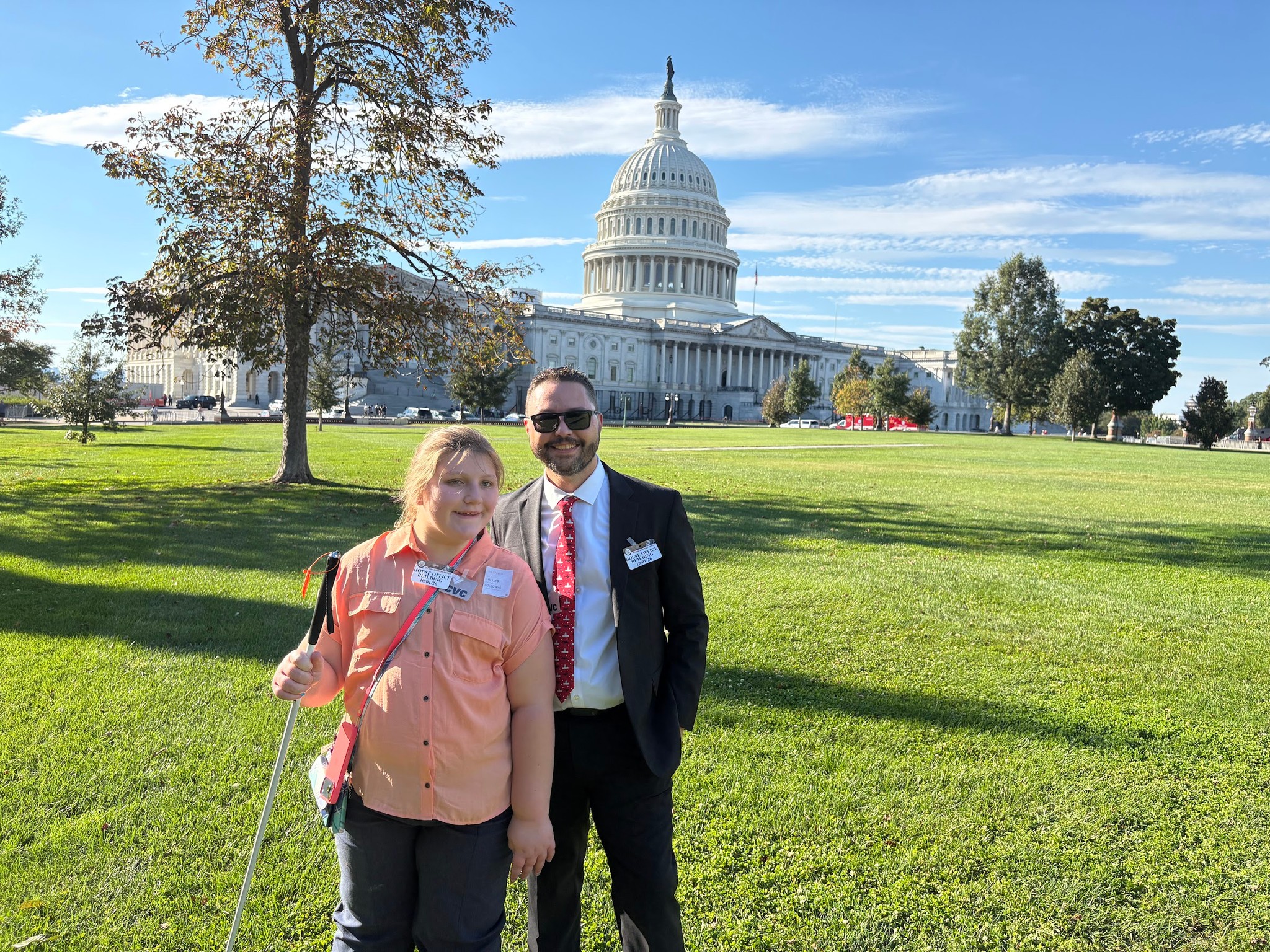 Isabelle and Rob Harris stand together on the lawn in front of the U.S. Capitol; Isabelle holds her white cane.