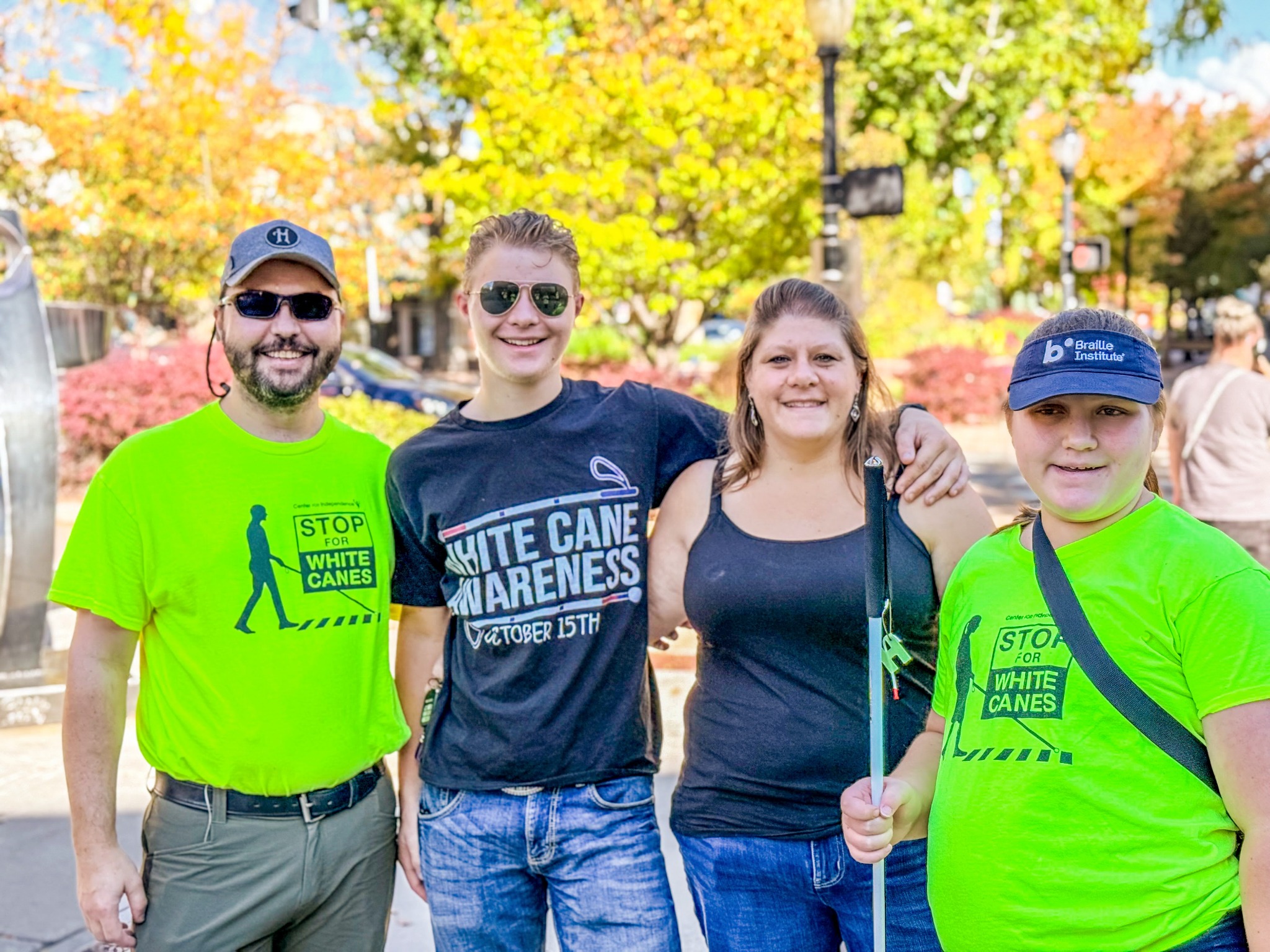 Rob, Tyler, Susan, and Isabelle Harris smile together at a White Cane Awareness event; Isabelle holds her white cane.